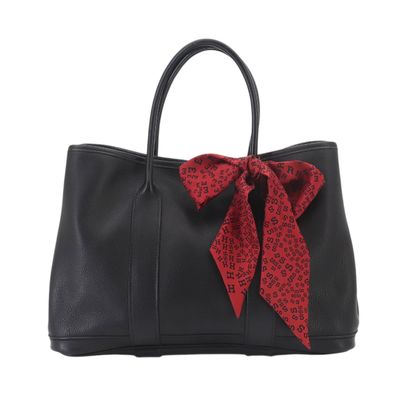 a black handbag with a red bow on the front