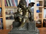 une statue représentant un petit ange assis sur une table