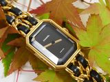 a gold and black watch on a chain with leaves