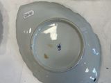 a white plate with a blue flower on it next to a plate with a blue flower on it
