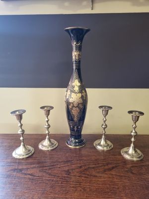 five silver candlesticks and a vase on a table