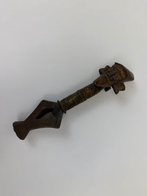 une vieille clé en bronze avec un manche en bois posée sur une surface blanche