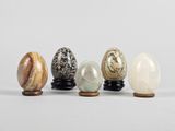 a group of five marble eggs sitting on top of a wooden stand