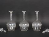 three clear glass vases sitting next to each other on a black surface