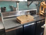 un plan de travail en acier inoxydable surmonté d'une planche à découper, dans une cuisine professionnelle