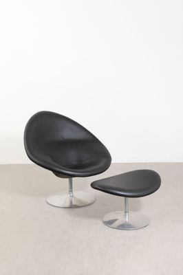 une photo représentant une chaise et un pouf noirs dans une pièce blanche
