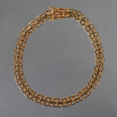 un gros plan d'un collier à chaîne dorée sur fond gris