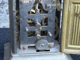 a small metal clock with gears inside of it