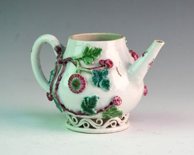 a white tea pot with green and pink decorations on it