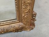 a mirror with a gold frame on the floor