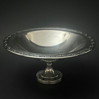 un plat ancien en argent posé sur un socle, sur fond noir
