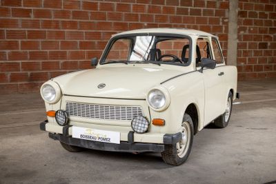 a small white car parked in front of a brick wall