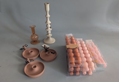 many different types of candles and candlesticks on the table