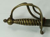 a gold colored sword with a twisted handle on a white surface