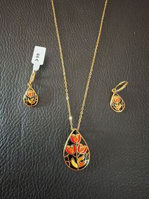 a gold necklace and earring set with a flower design