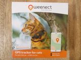 un chat assis sur une table avec un traceur GPS