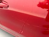 a close up of a red car door handle with a teddy bear on it