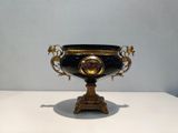 a black and gold vase sitting on a white table