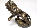 bronze statue of a lion on a rock on a white background
