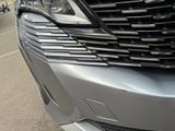 the front end of a silver car with a motorcycle in the background