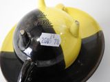 une assiette noire et jaune sur laquelle est représentée une théière noire et jaune