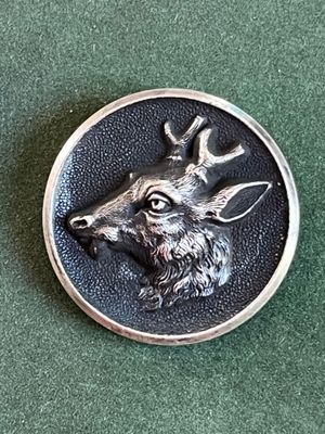 un gros plan d'un bouton en métal orné d'une tête de cerf