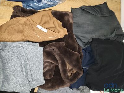 a pile of clothes on the floor next to a bottle of water