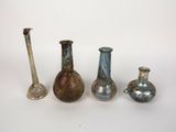 Plusieurs vases de différentes couleurs sont alignés sur une surface blanche