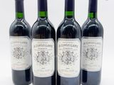 quatre bouteilles de vin sont alignées sur une surface blanche