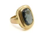 gros plan d'une bague en or avec une pierre bleue