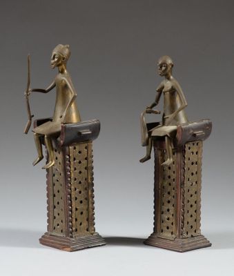 pair of bronze figurines of a woman sitting on top of a table