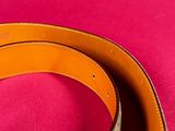 a close up of a brown belt on a pink surface