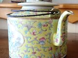 a yellow tea pot sitting on a table with a spoon in it