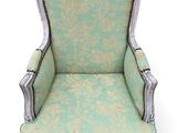 an old chair with a green upholstered back and silver trim