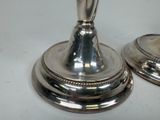 two silver candlesticks sitting on top of each other