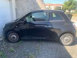 the small black car is parked in front of a garage