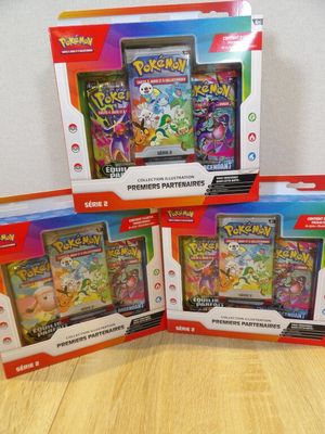 three boxes of pokemon cards sitting on top of a wooden table
