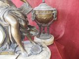 a statue of a woman sitting on a table next to a clock