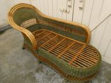 une chaise longue en osier posée à même le sol devant une porte blanche