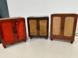 trois petites armoires en bois sont alignées sur une surface blanche