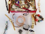 une boîte rouge remplie de bijoux variés, posée sur une surface blanche