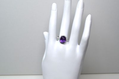 une main sur laquelle est passée une bague sertie d'une pierre violette