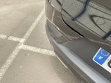 a black car parked in a parking lot with graffiti on it