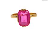 un gros plan d'une bague en pierre rose sur fond blanc