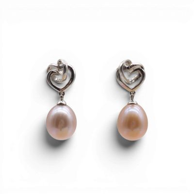 une paire de boucles d'oreilles roses en perles et argent sur fond blanc