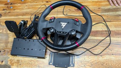 the steering wheel and pedals are on the table next to the game controller