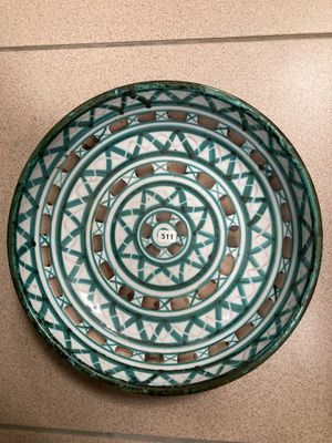 un bol vert et blanc accroché au mur, à côté d'une assiette noire et blanche