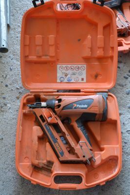 an orange tool case with a stapler, nail gun, and other tools in it