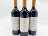 trois bouteilles de vin rouge posées l'une à côté de l'autre sur une surface blanche