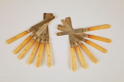 une paire d'ustensiles vintage à manche en bois posés sur une surface blanche